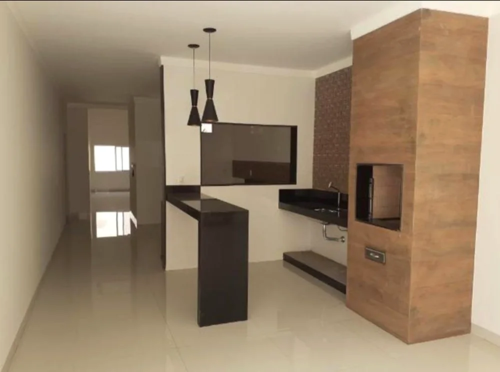 Sala e cozinha integradas com bancada e churrasqueira